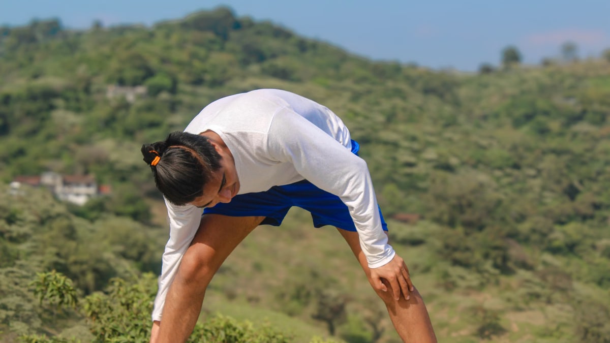 Man practicing yoga outdoors in the scenic hills of Huehuetla, Puebla, Mexico with a focus on well-being.